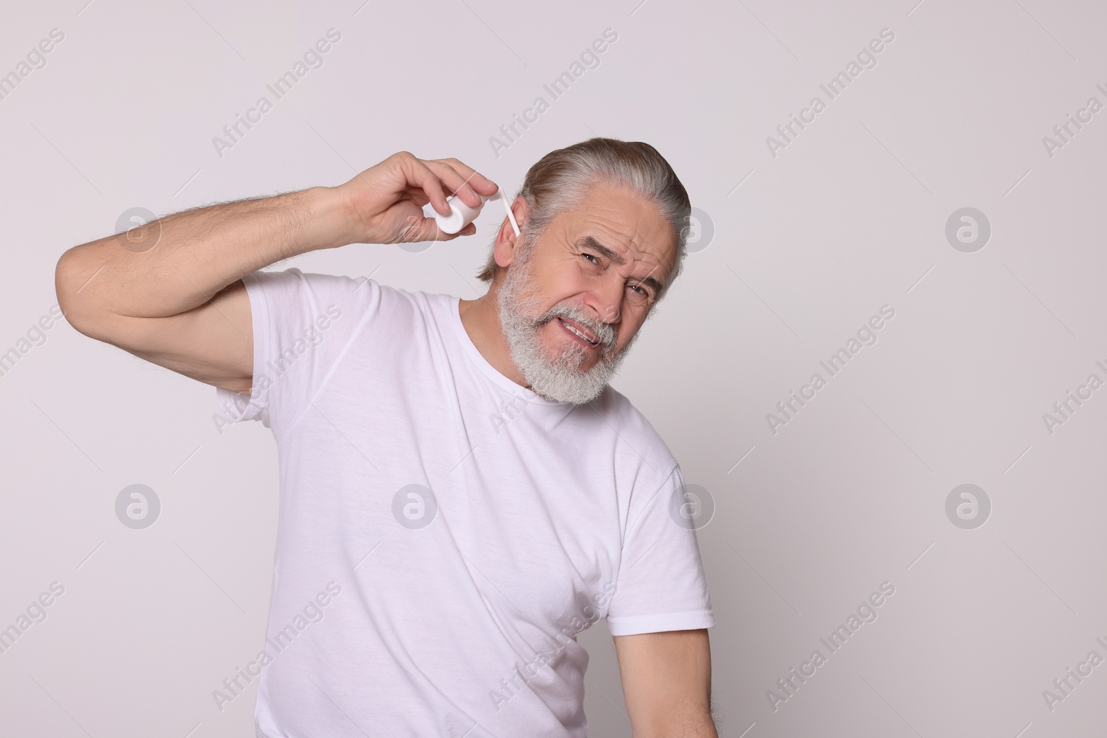 Photo of Senior man using ear spray on white background, space for text