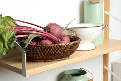 Photo of Raw ripe beets in wicker bowl on shelf indoors