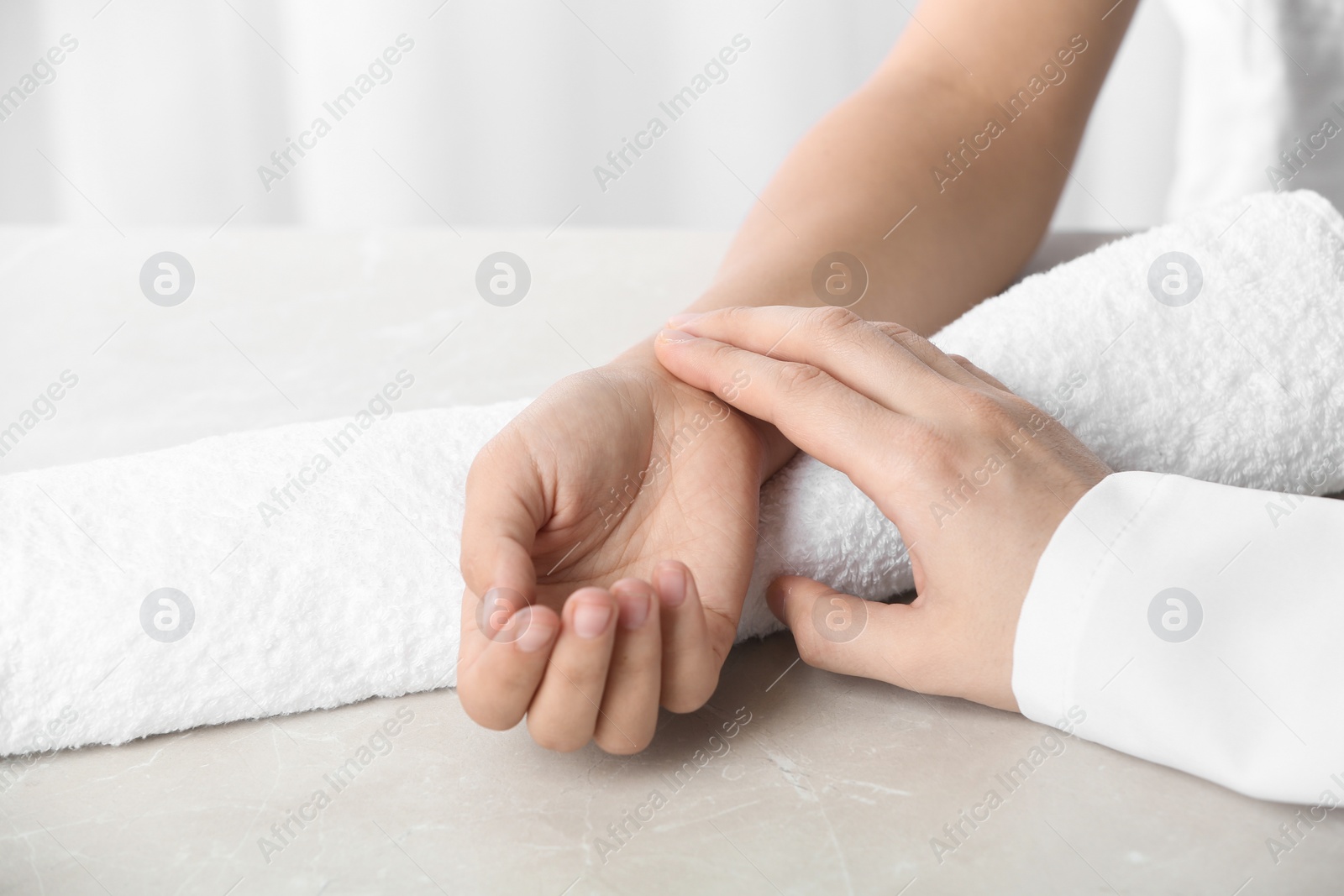 Photo of Doctor checking patient's pulse on table, closeup