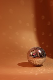 Photo of Shiny disco ball on orange background. Space for text