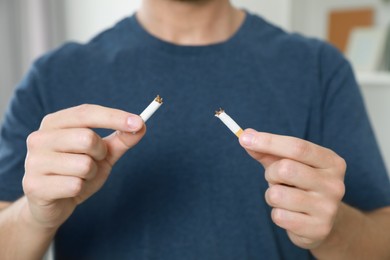 Stop smoking concept. Man holding pieces of broken cigarette indoors, closeup