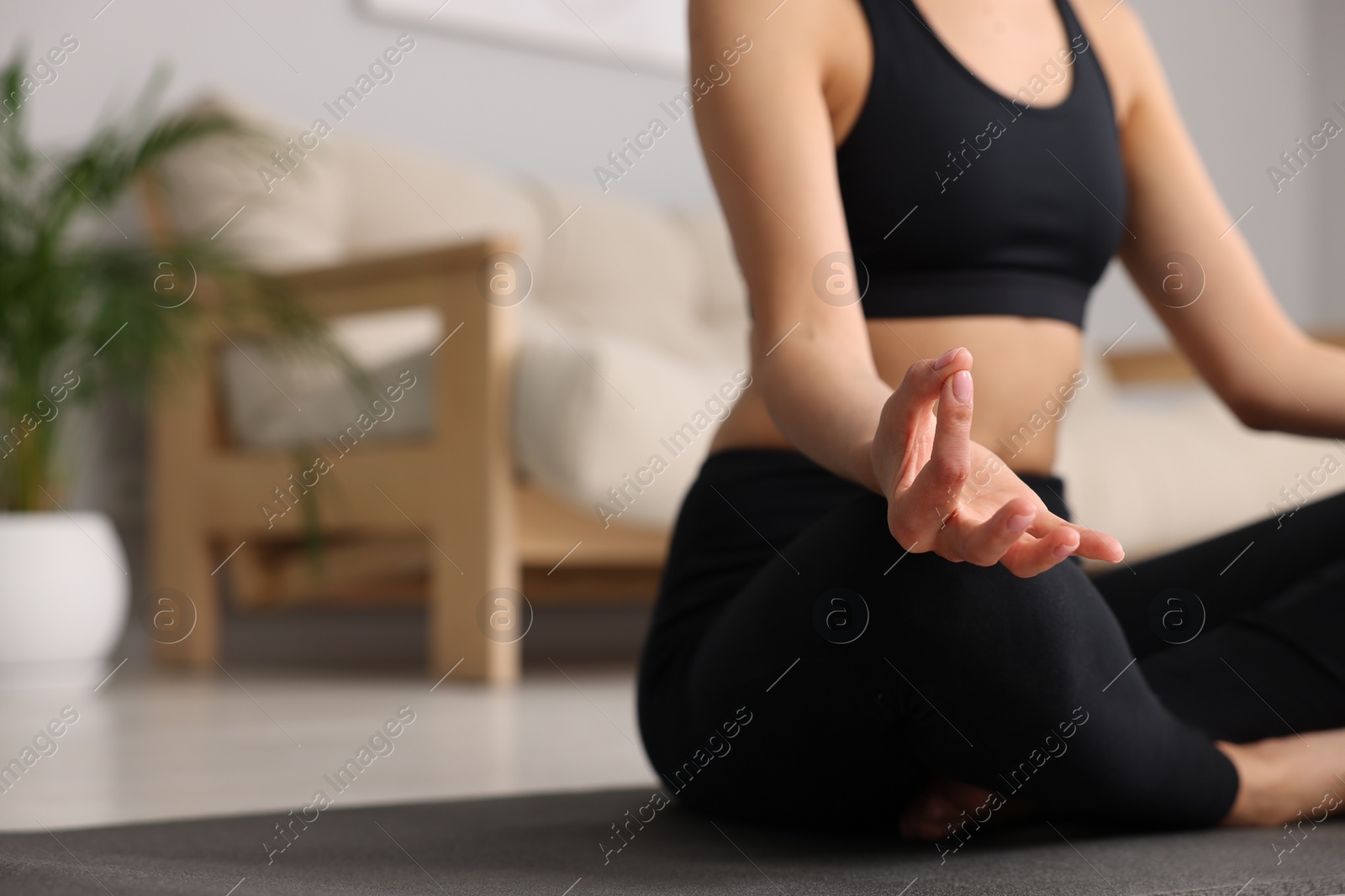 Photo of Woman practicing Padmasana on yoga mat at home, closeup and space for text. Lotus pose