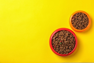 Bowls with food for cat and dog on color background. Pet care