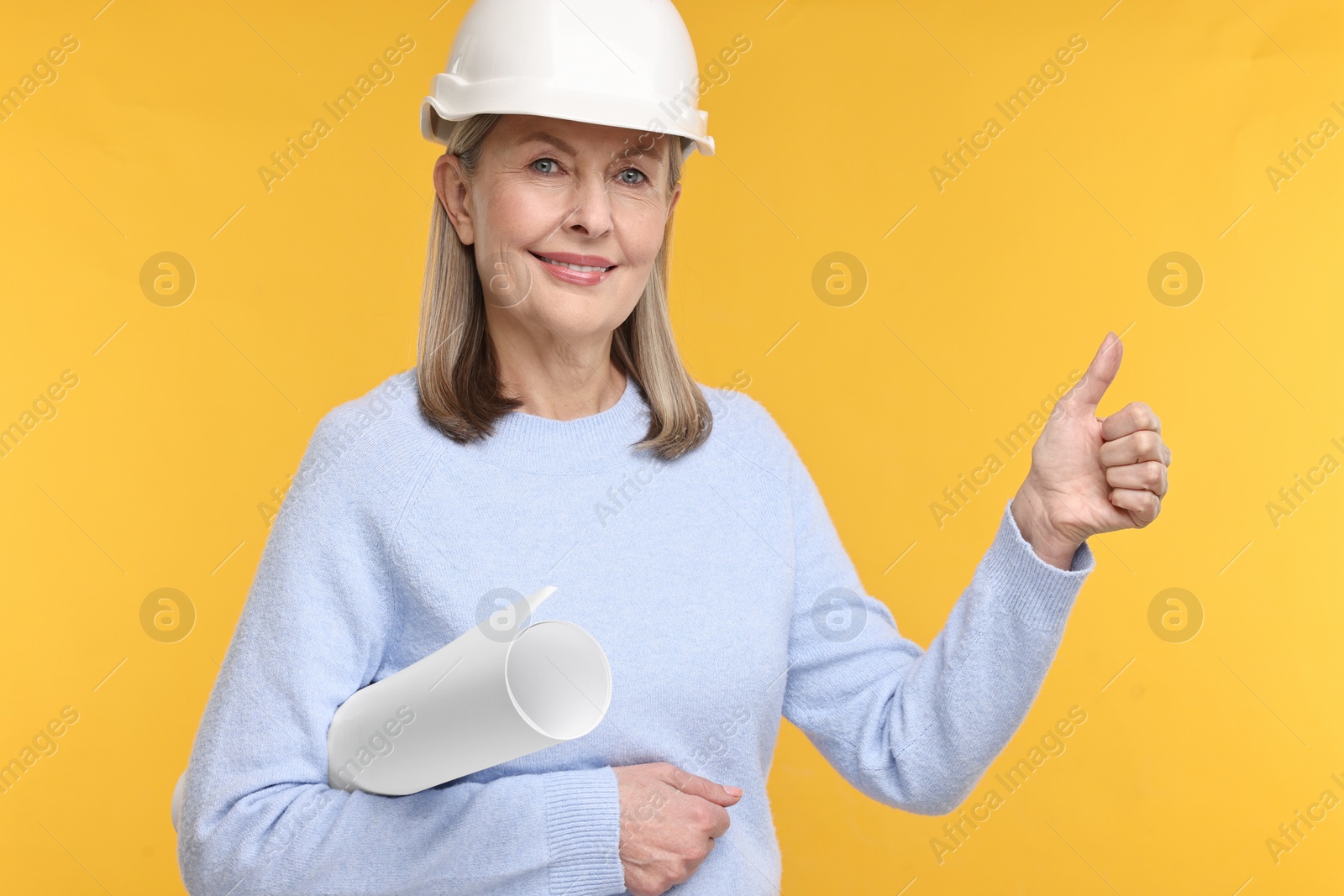 Photo of Architect in hard hat with draft showing thumbs up on background