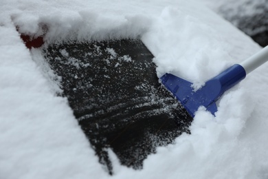 Photo of Cleaning car from snow outdoors on winter day, closeup. Frosty weather