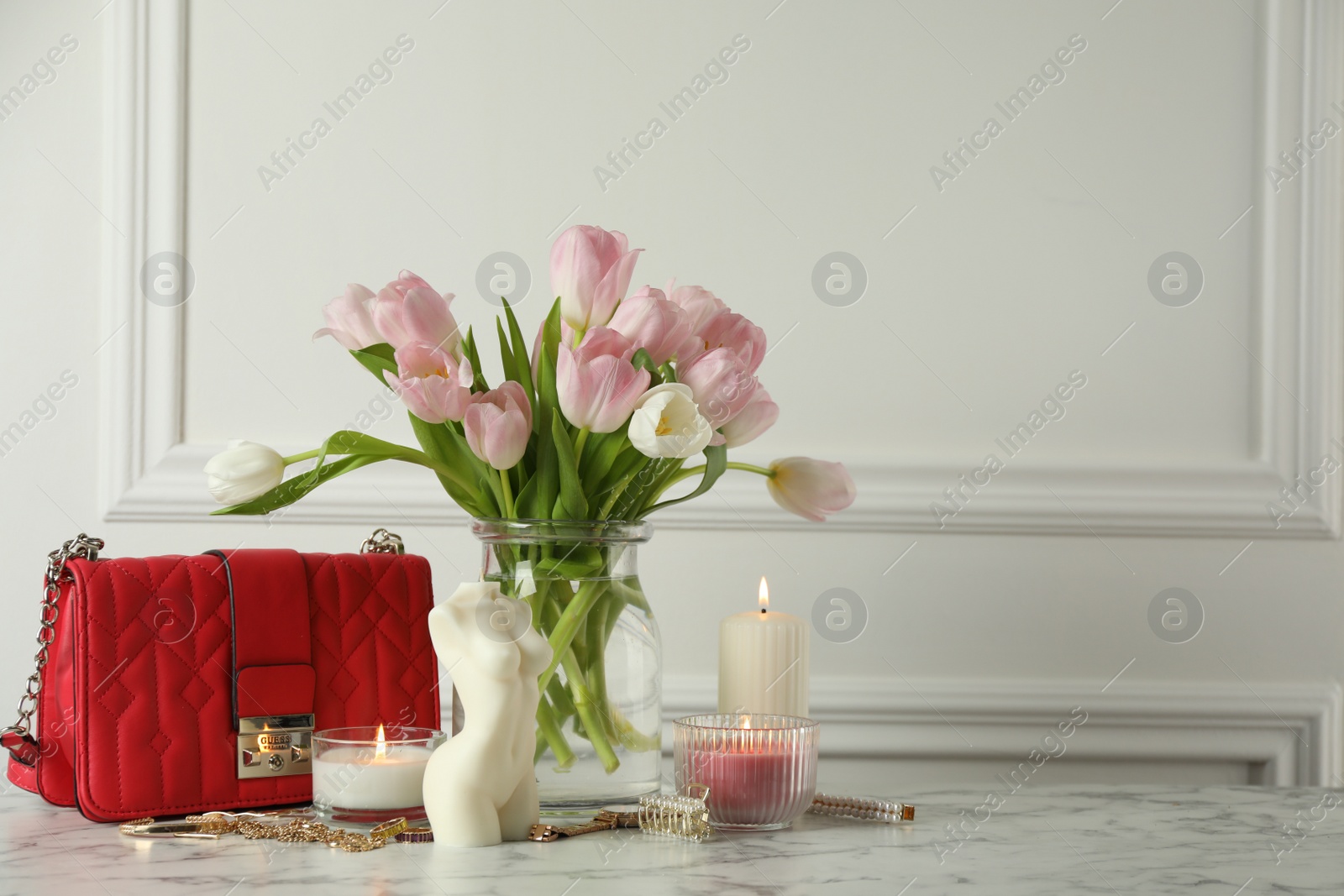 Photo of Beautiful female body shaped candle and tulips on white marble table, space for text. Stylish decor