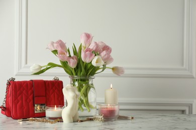 Beautiful female body shaped candle and tulips on white marble table, space for text. Stylish decor