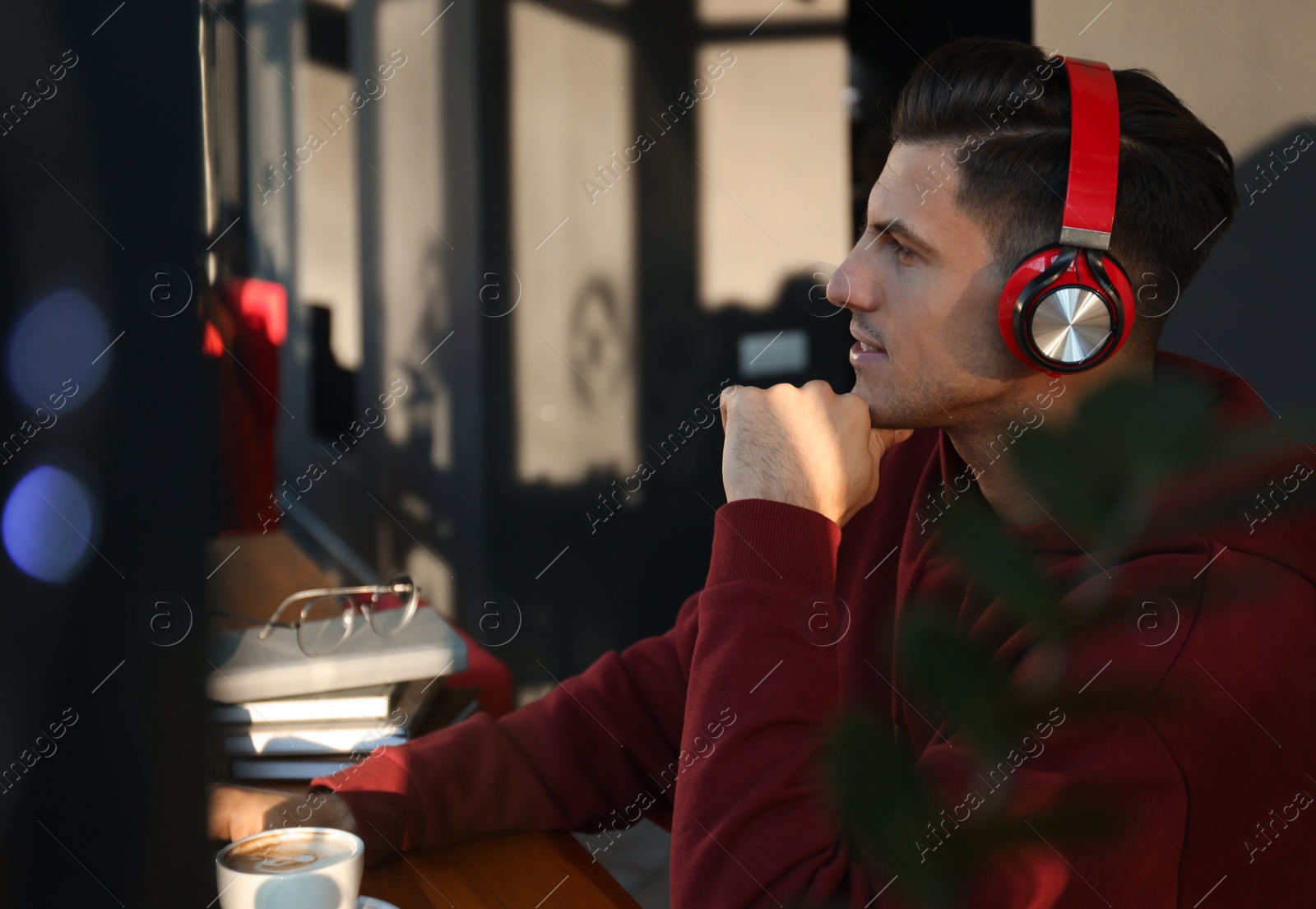 Photo of Man listening to audiobook at table in cafe