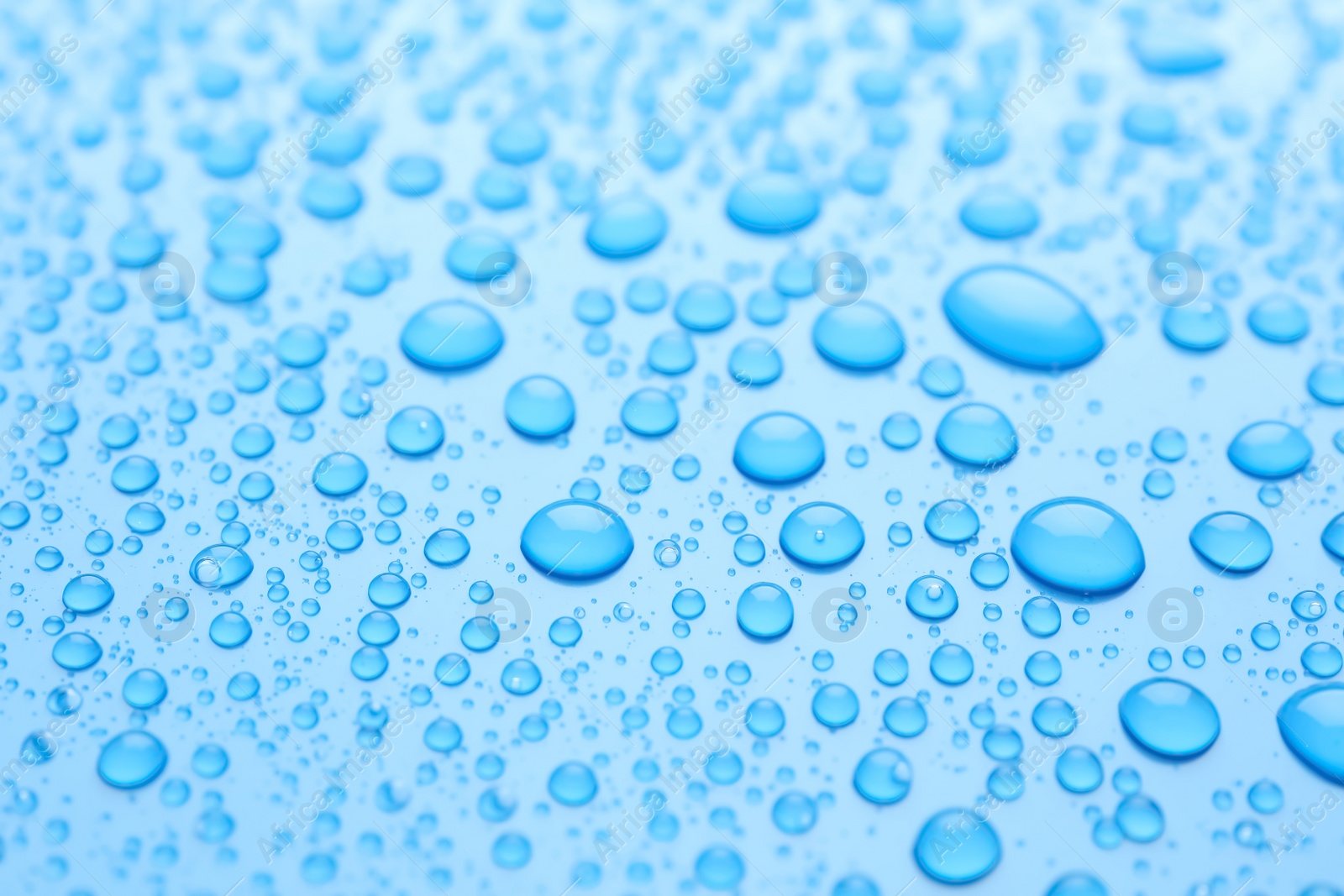 Photo of Water drops on light blue background, closeup view