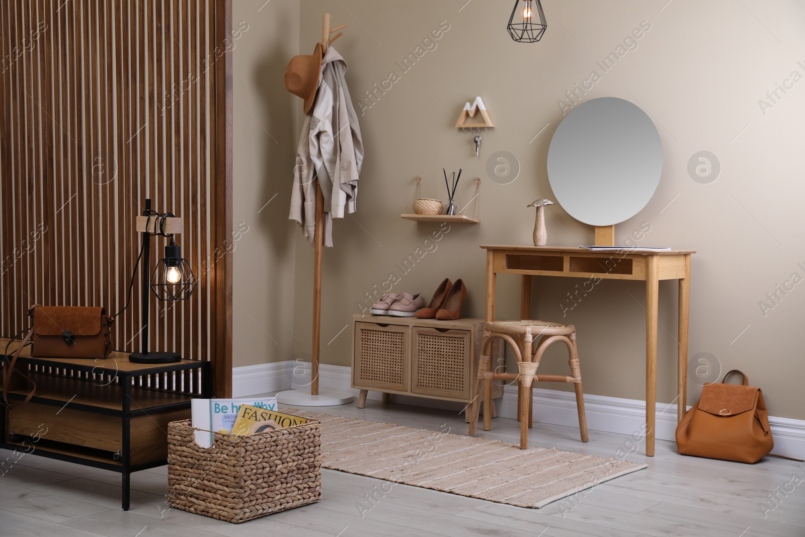 Photo of Modern hallway interior with stylish furniture, round mirror and wooden hanger for keys on beige wall