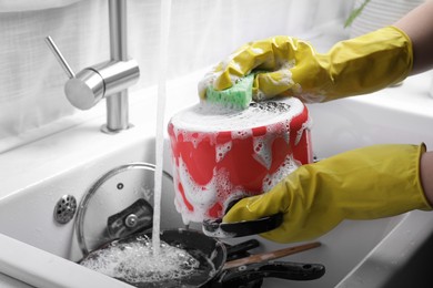 Photo of Woman washing pot in kitchen sink, closeup