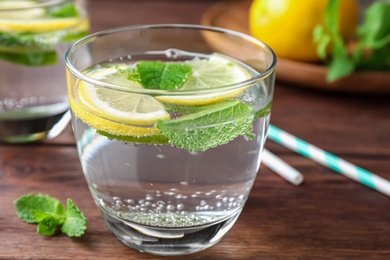 Photo of Tasty refreshing lemonade on wooden table, closeup. Summer drink