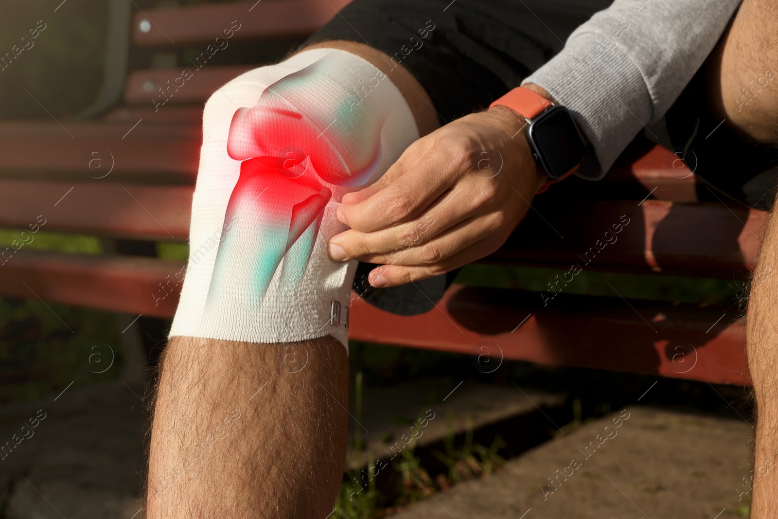 Image of Man applying bandage onto his injured knee on wooden bench outdoors, closeup