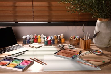 Artist's workplace with soft pastels, laptop and drawing pencils on table