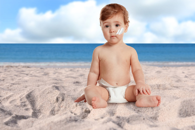 Image of Adorable baby with sun protection cream on face at sandy beach