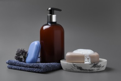 Photo of Soap bar, bottle dispenser and towel on grey background