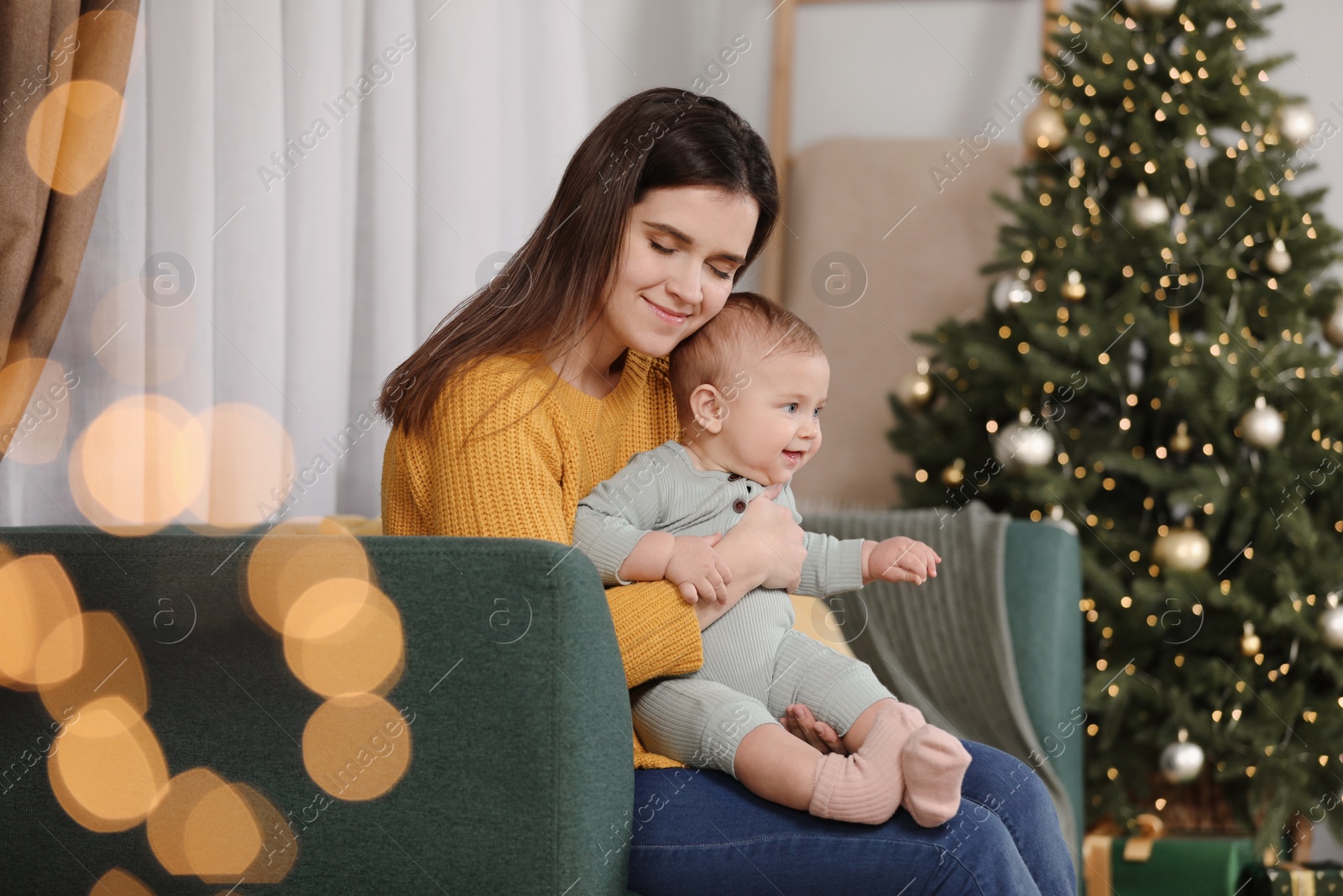 Photo of Happy young mother with her cute baby in room decorated for Christmas. Winter holiday