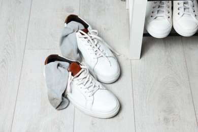 Sneakers with dirty socks on white wooden floor indoors