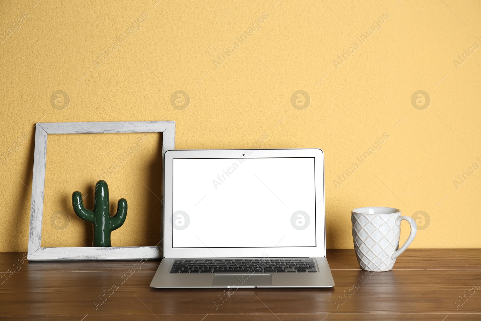 Photo of Modern laptop monitor on table against color wall. Mock up with space for text