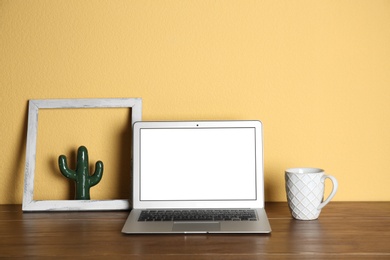 Photo of Modern laptop monitor on table against color wall. Mock up with space for text