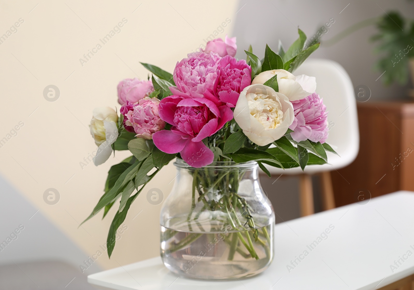 Photo of Vase with bouquet of beautiful peonies on table in room