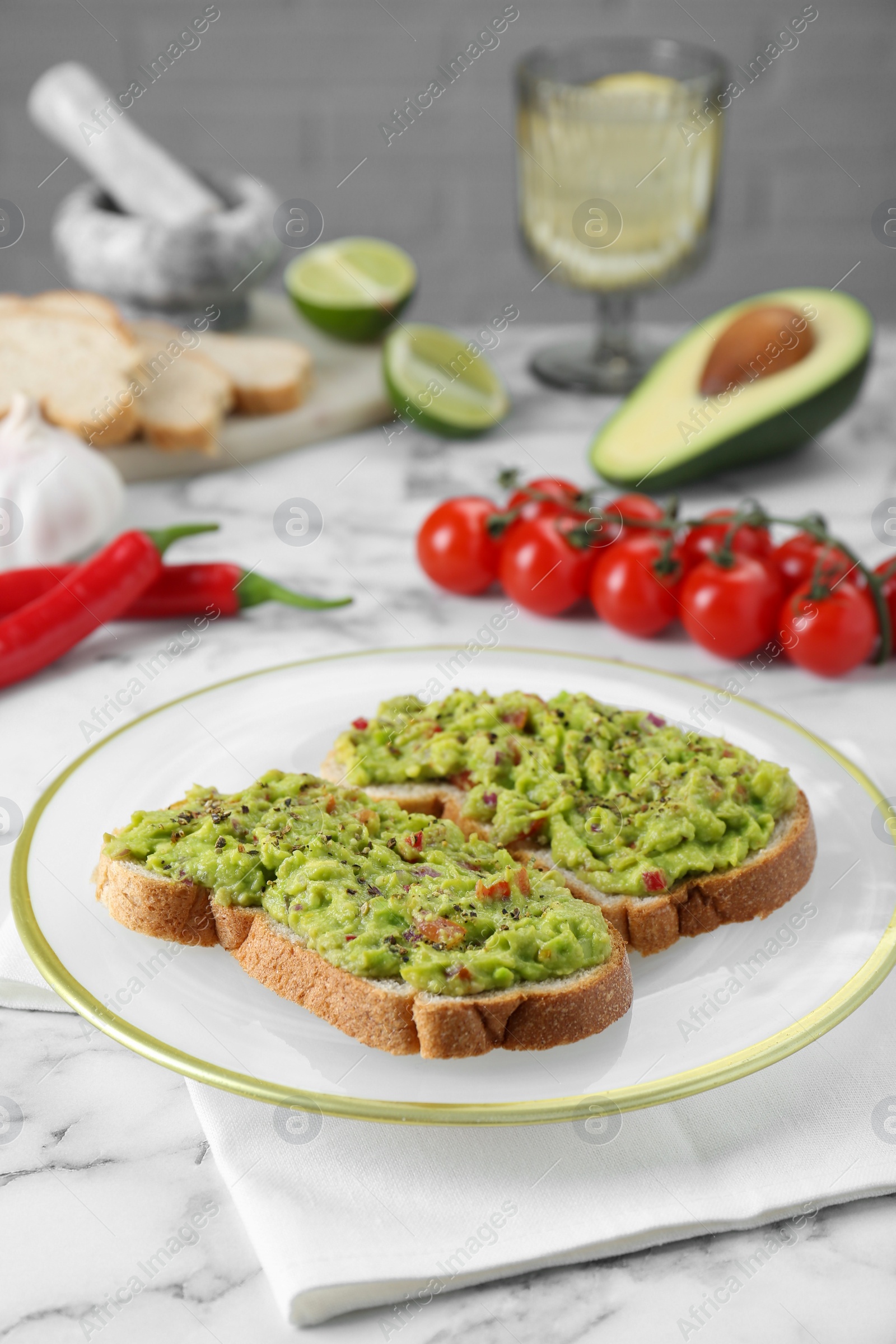 Photo of Delicious sandwiches with guacamole and ingredients on white table