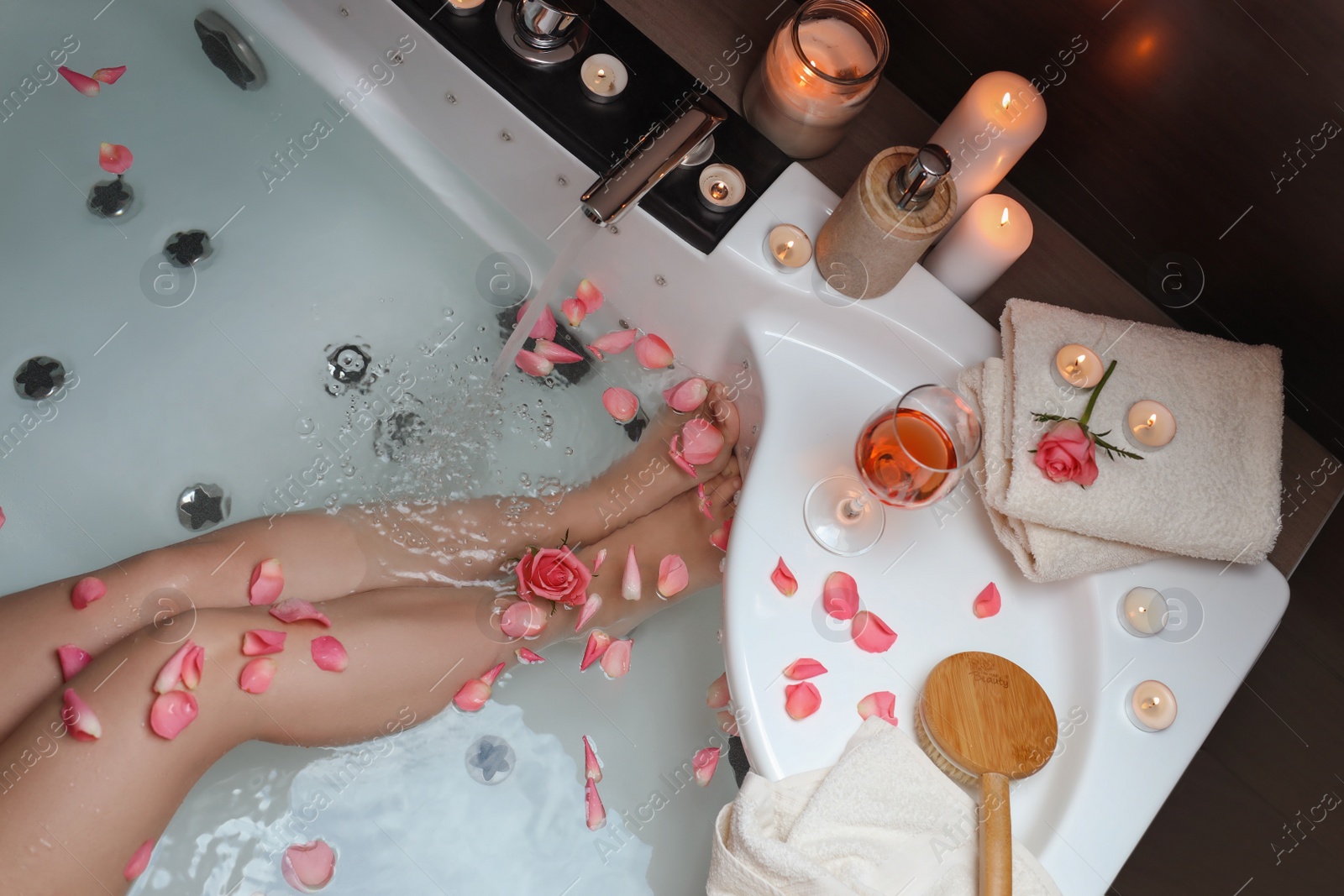 Photo of Woman taking bath with rose petals, above view. Romantic atmosphere