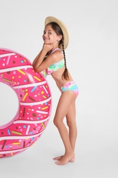 Cute little child in beachwear with bright inflatable ring on white background