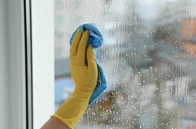 Woman cleaning window at home, closeup view