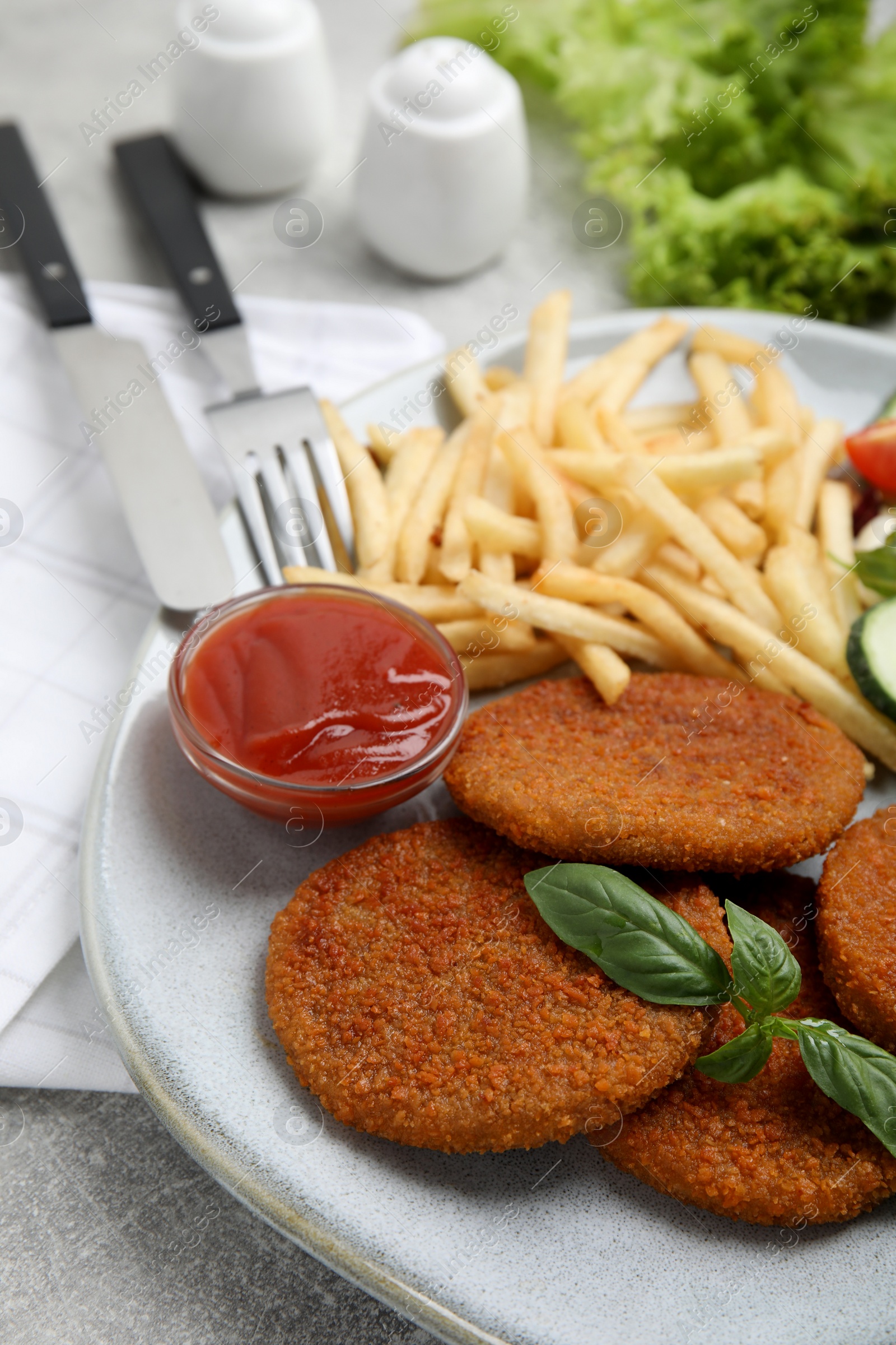Photo of Delicious fried breaded cutlets with garnish on grey table, closeup