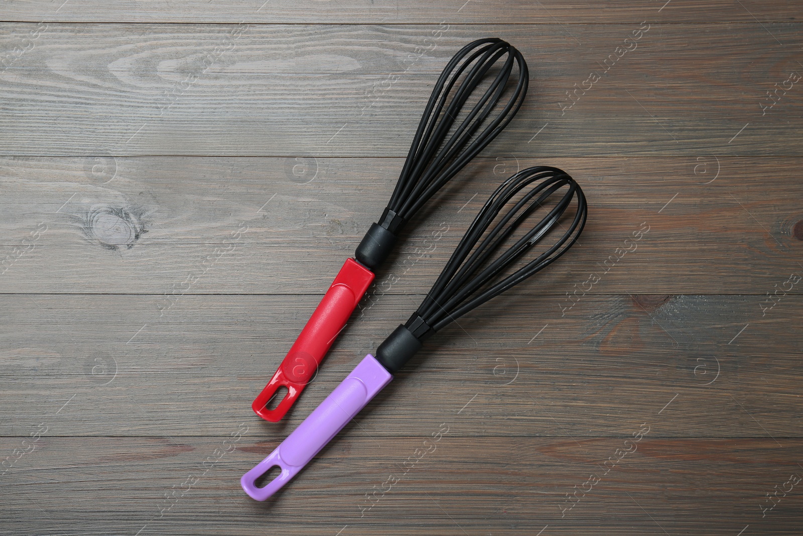 Photo of Two whisks on wooden table, top view. Kitchen tool