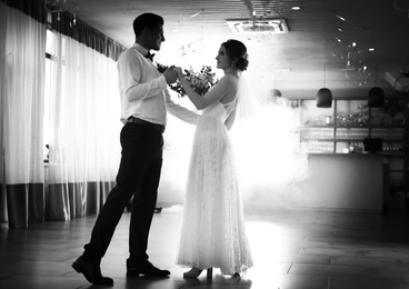 Happy newlywed couple dancing together in festive hall