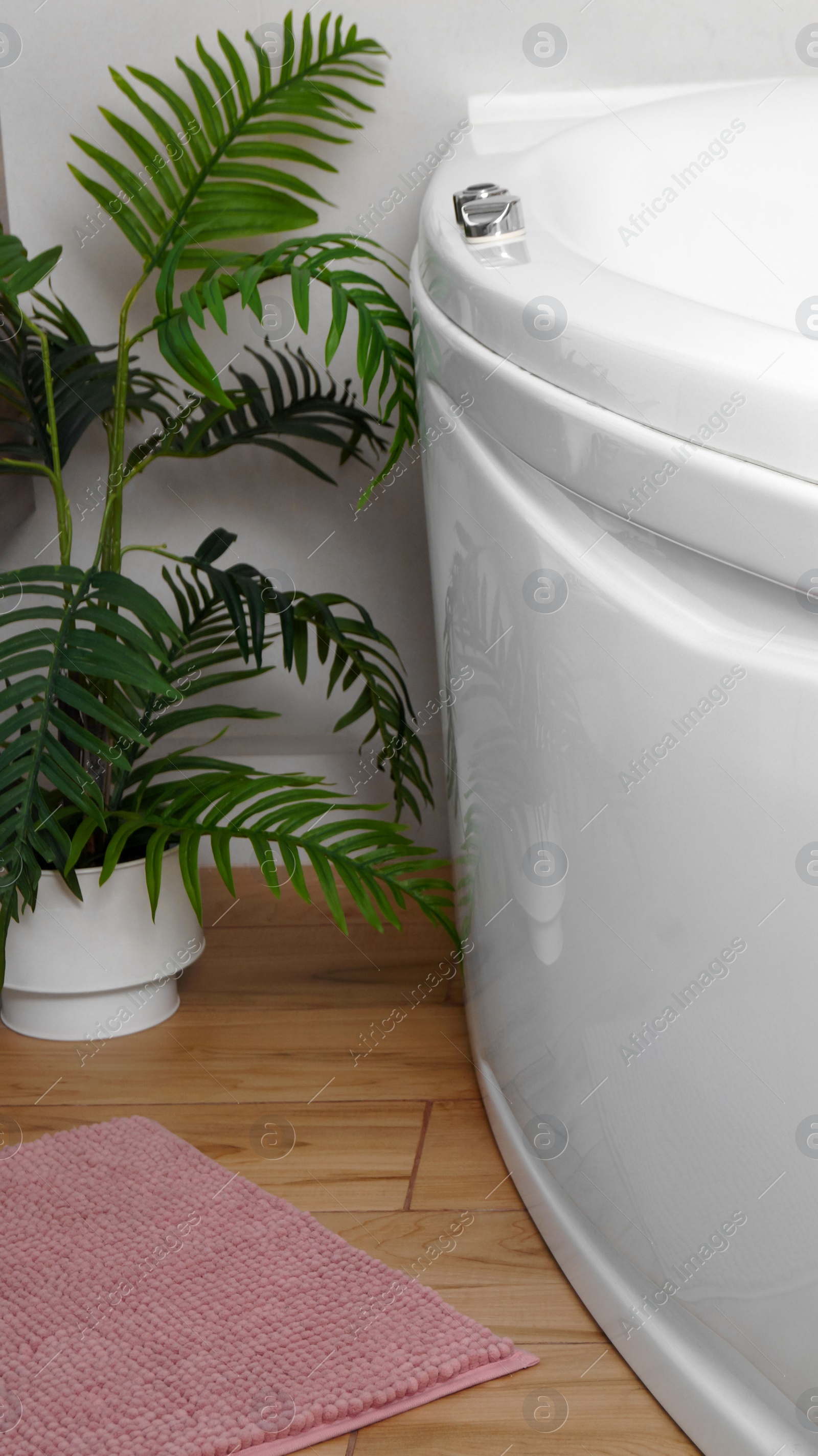 Photo of Pink mat near tub on wooden floor in bathroom