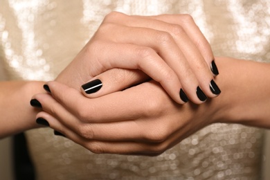 Photo of Woman in gold dress with black manicure, closeup. Nail polish trends