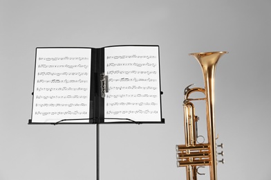 Photo of Trumpet and note stand with music sheets on grey background