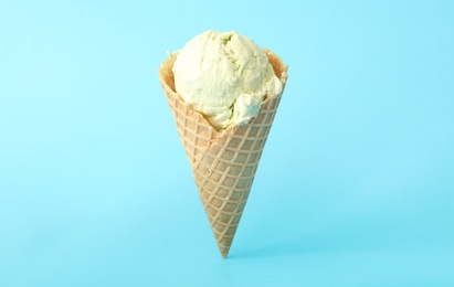 Photo of Delicious ice cream in waffle cone on light blue background