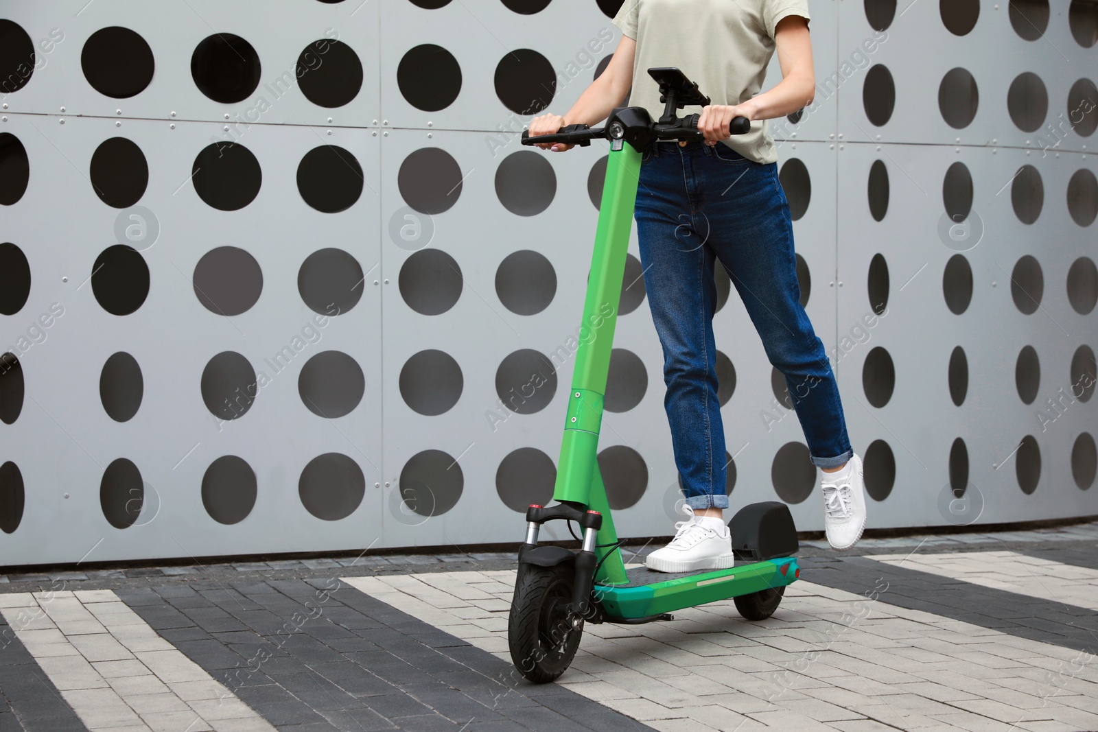 Photo of Woman riding modern electric kick scooter on city street, closeup. Space for text