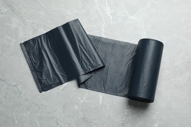 Roll of black garbage bags on light grey marble table, top view