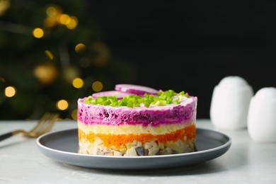 Photo of Herring under fur coat salad on light grey table against blurred festive lights, space for text. Traditional Russian dish