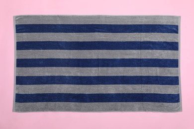 Striped beach towel on pink background, top view