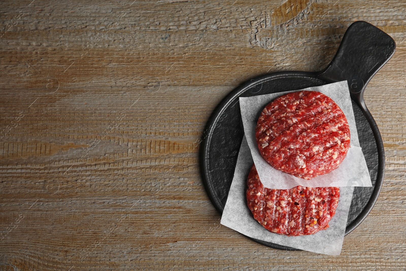 Photo of Raw meat cutlets for burger on wooden table, top view. Space for text