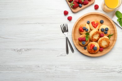 Photo of Delicious cottage cheese pancakes with fresh berries and honey on white wooden table, flat lay. Space for text