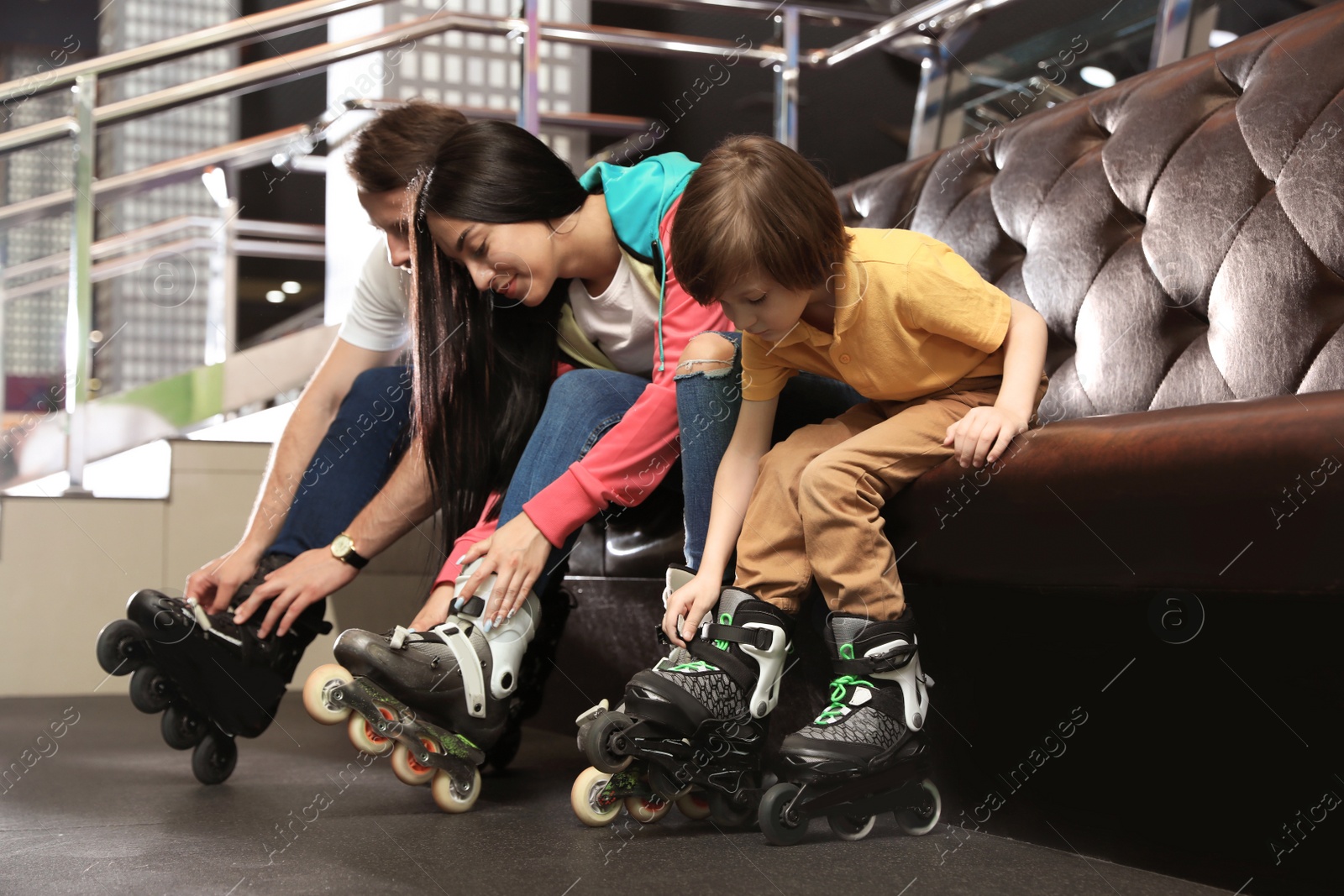 Photo of Happy family putting on roller skates indoors