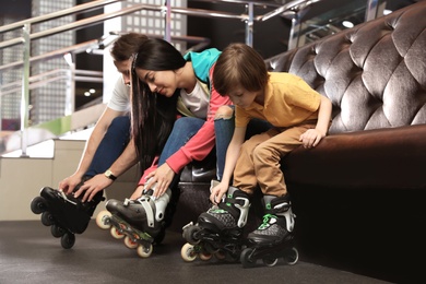 Happy family putting on roller skates indoors