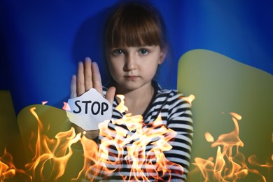 Image of Multiple exposure of little girl with sign STOP, Ukrainian flag and fire