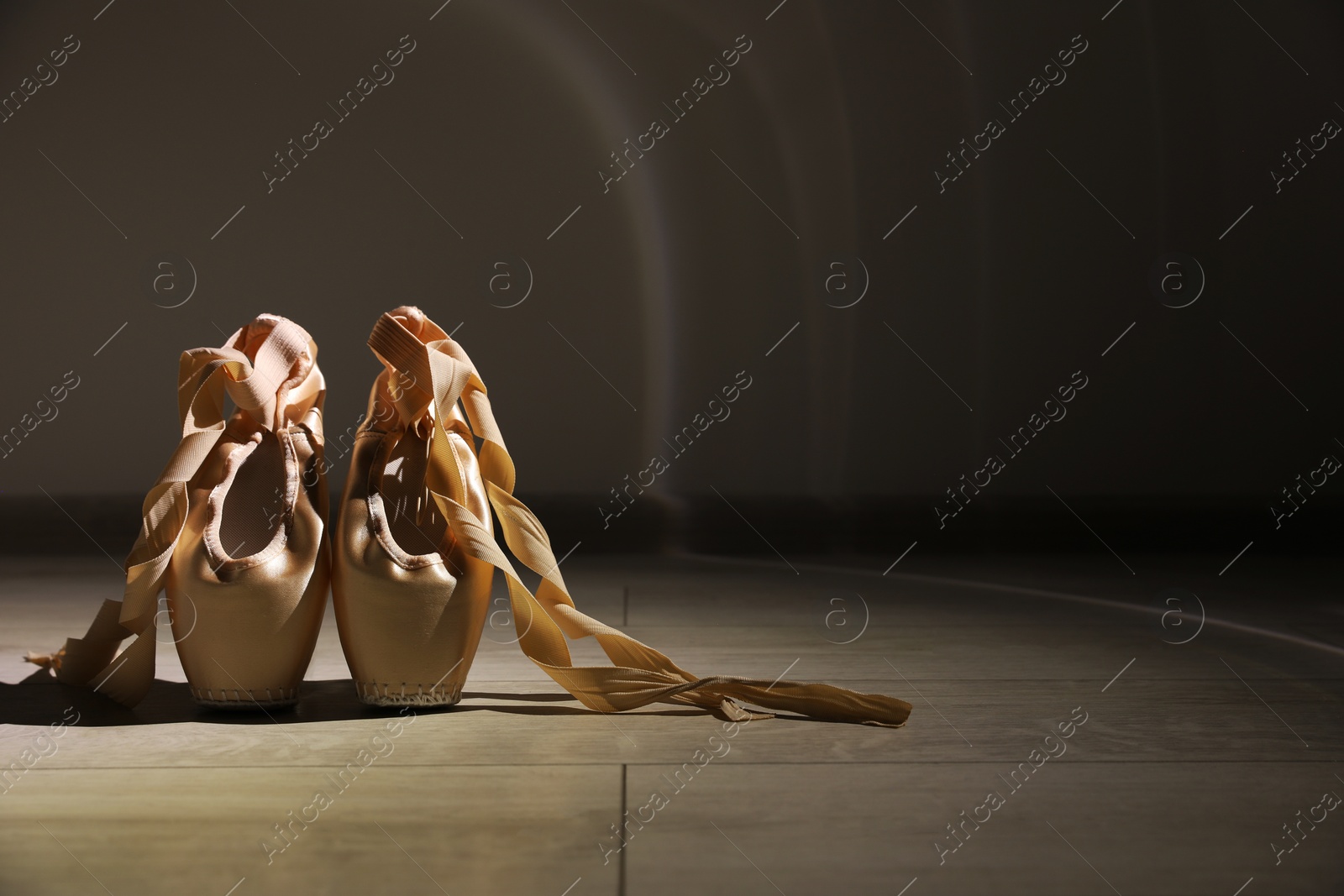 Photo of Ballet shoes. Elegant pointes on wooden floor indoors, space for text