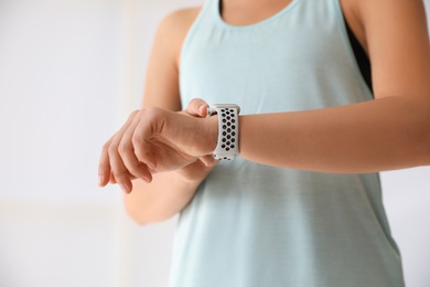 Photo of Woman checking fitness tracker indoors, closeup view