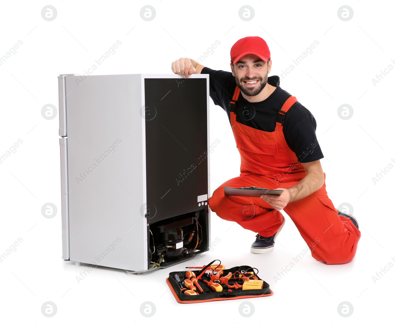 Photo of Male technician with clipboard and tools near broken refrigerator on white background