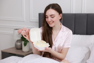 Photo of Beautiful young woman holding her Birthday cake on bed in room