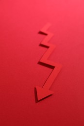 Photo of One zigzag paper arrow on red background, closeup